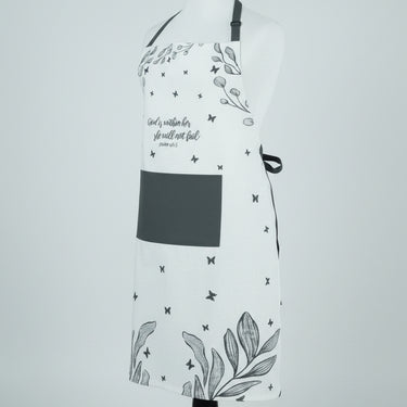 A white kitchen apron with black text reading 'God is nearer to thee than any other living creature' and 'Jesus is the only true God', decorated with black stars and botanical leaf patterns, displayed on a white mannequin torso against a light gray background.