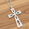 Silver cross pendant on a chain against a wooden background