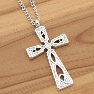 Silver cross pendant on a chain against a wooden background