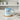 A ceramic mug with a sky-blue and white watercolor design, featuring the text 'Be Still in the Presence of God Psalm 46:10' and a heart-shaped handle, styled on a white wooden table with a small potted succulent and a folded napkin.