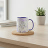 A white ceramic mug with a purple handle and interior, featuring the printed text 'I WILL NEVER Leave YOU FOR FORSAKE YOU JOSEPH 1:9' and purple floral illustrations. The mug sits on a round cork coaster on a light wood table, with a blurred background showing a window, books, and a potted plant.